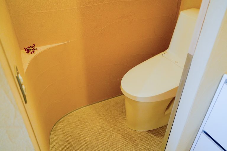 福岡ウェルネスパートナー様のトイレスペース。珪藻土宙で施工された柔らかな曲面の入隅壁と落ち着いた内装